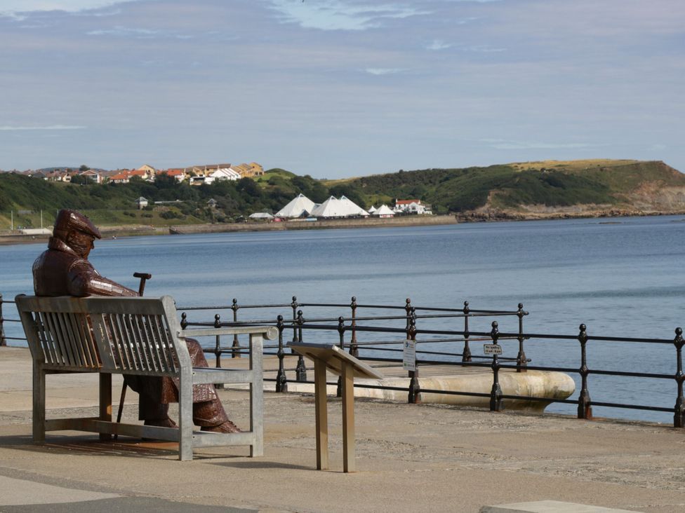 A statue seated on a bench overlooking the sea at Evergreen Pines in Cayton Bay near Scarborough