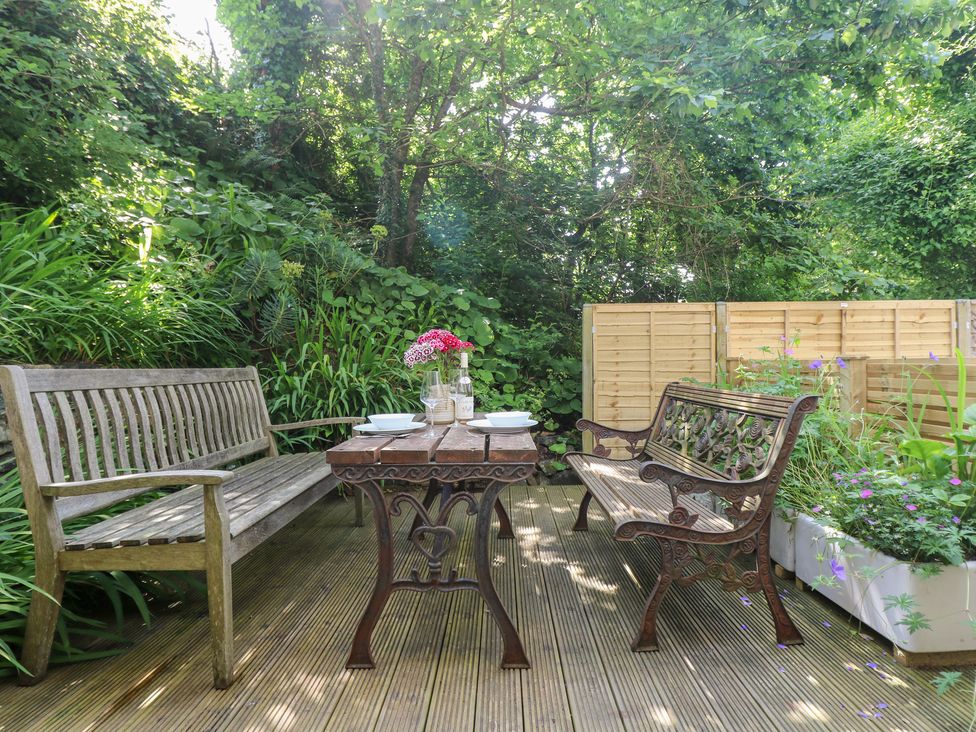 A garden with a wooden table and benches at Oofoo’s Barn in Mullion