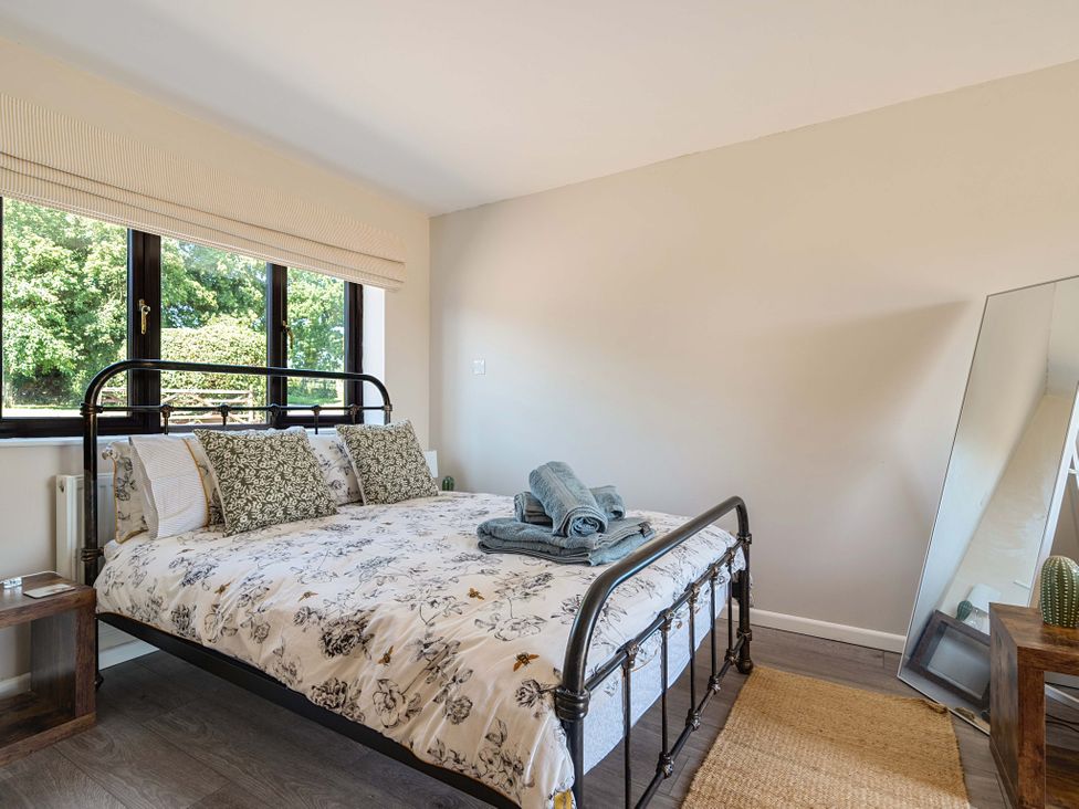 A bedroom with a bed and mirror at Piglet Corner in Culmstock