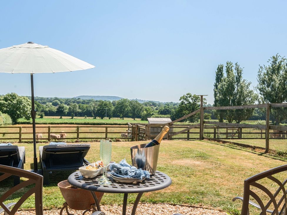 An outdoor area with table and chairs overlooking a field at Piglet Corner in Culmstock