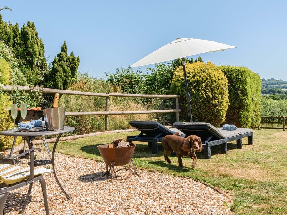 An outdoor area with sun loungers and a table at Piglet Corner in Culmstock