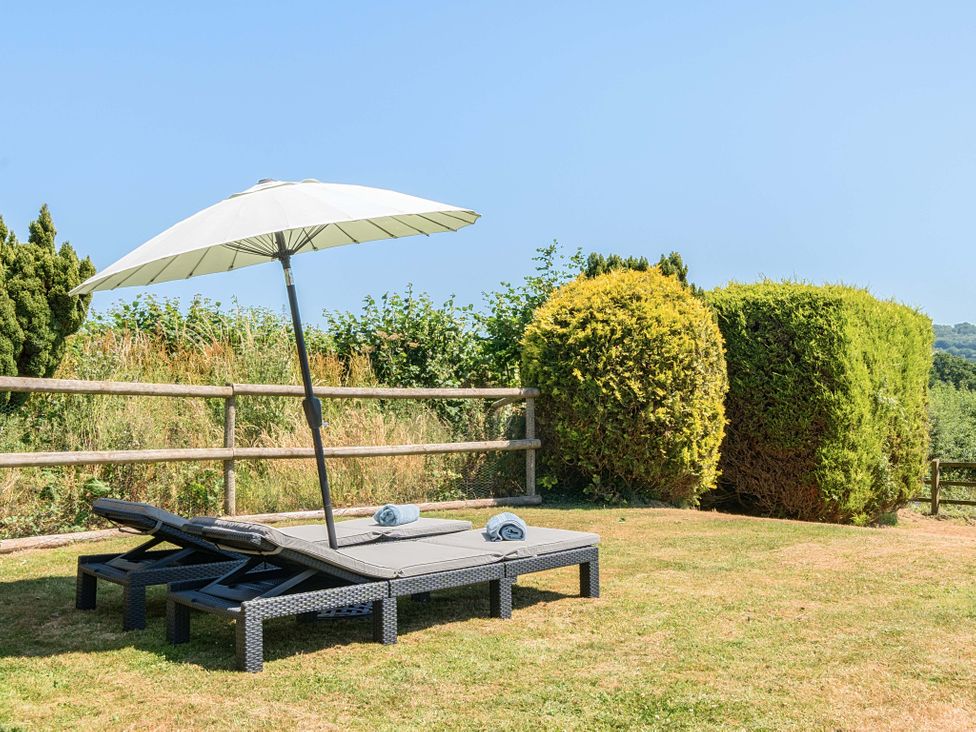 A garden with lounge chairs and an umbrella at Piglet Corner in Culmstock