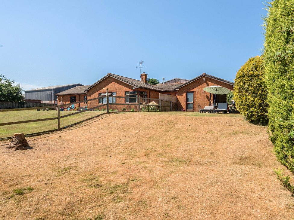 A garden with a house and patio umbrella at Piglet Corner in Culmstock