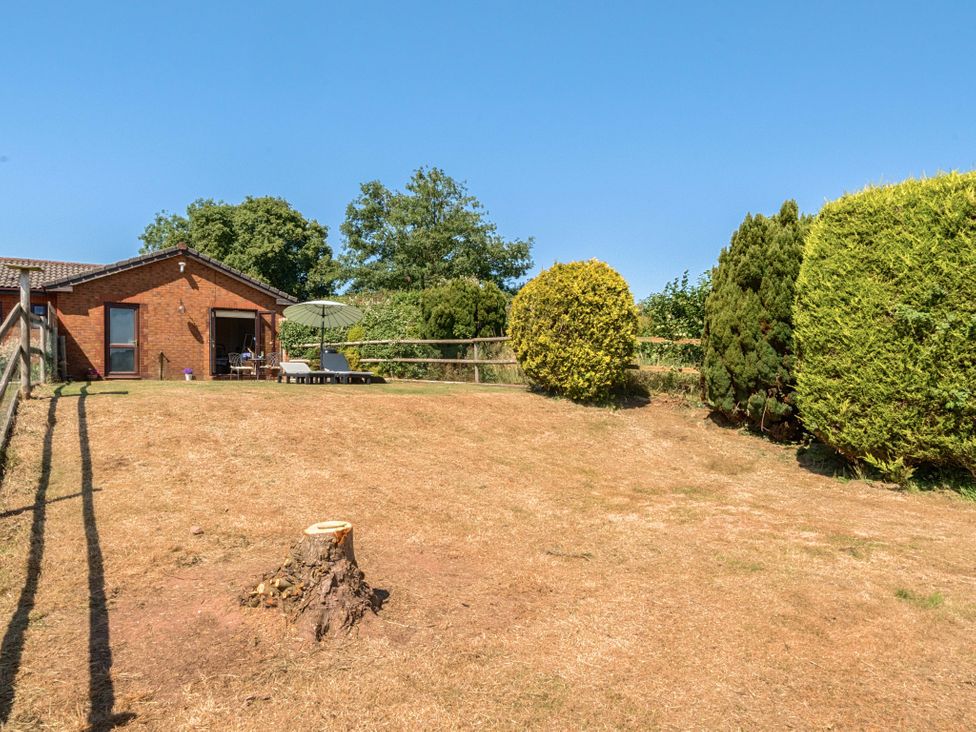 A garden with a house and seating area at Piglet Corner in Culmstock