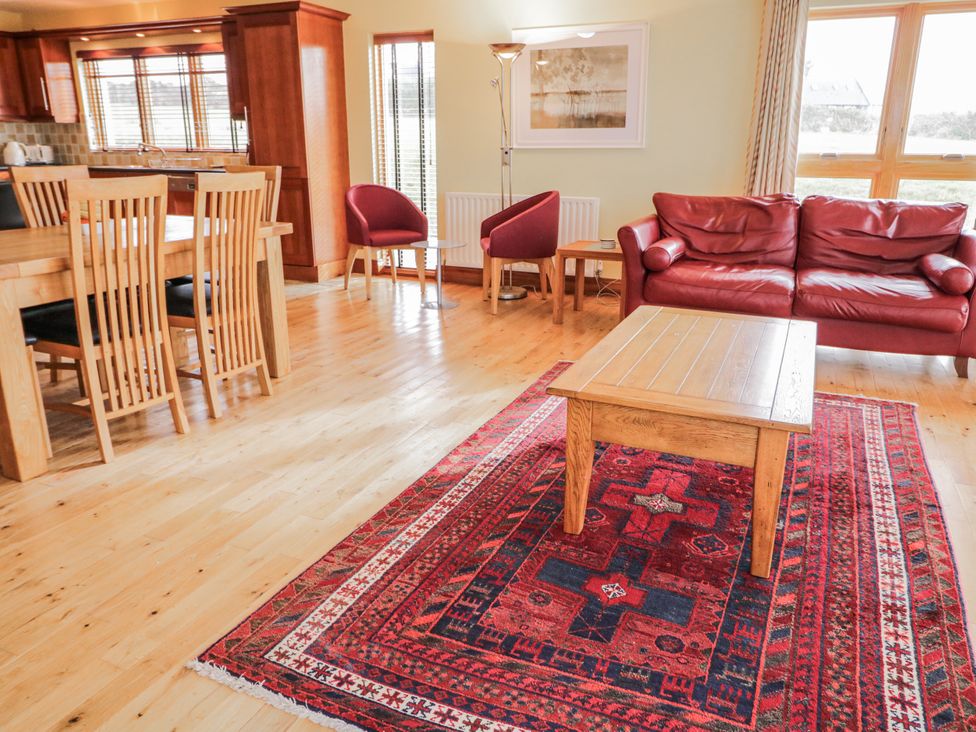A living room with a dining area and red sofa at Cashelrehine Falcarrheh