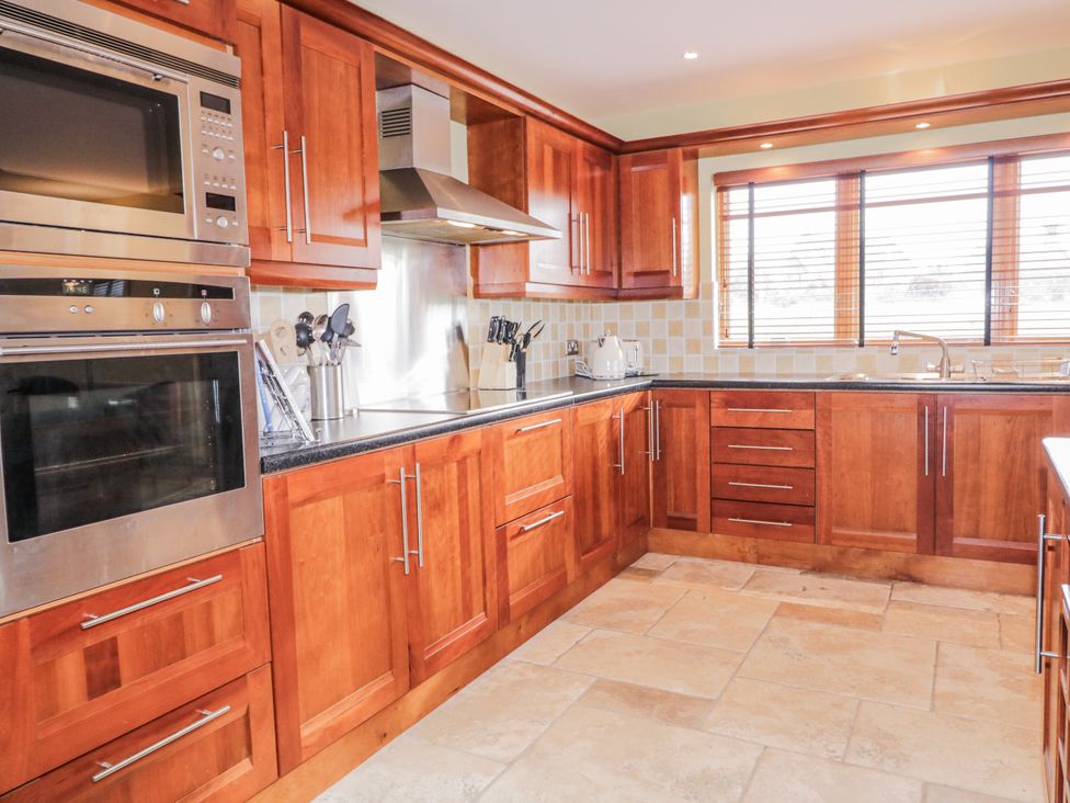 A kitchen with wooden cabinets and appliances at Cashelrehine Falcarrheh