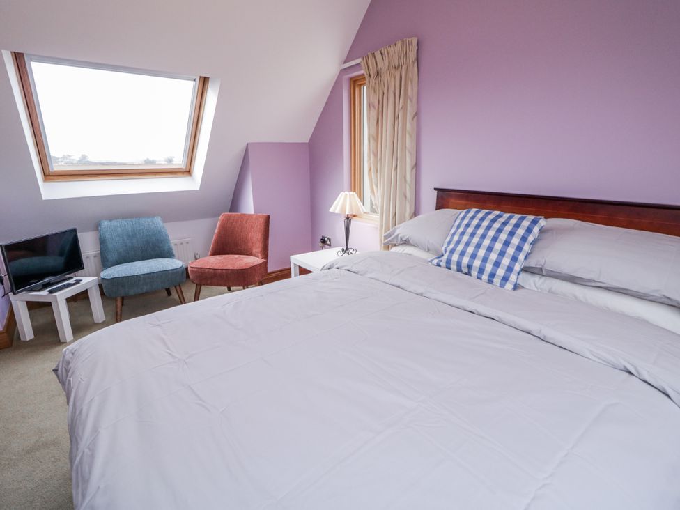 A bedroom with a bed and two chairs at Cashelrehine in Falcarrheh