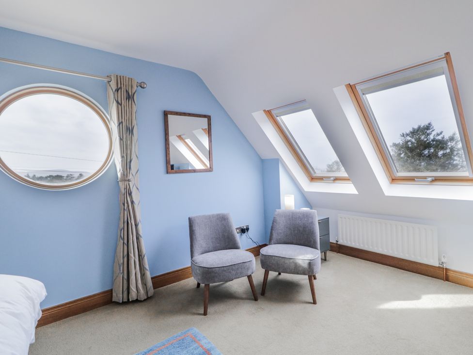 A bedroom with two chairs and round window at Cashelrehine Falcarrheh