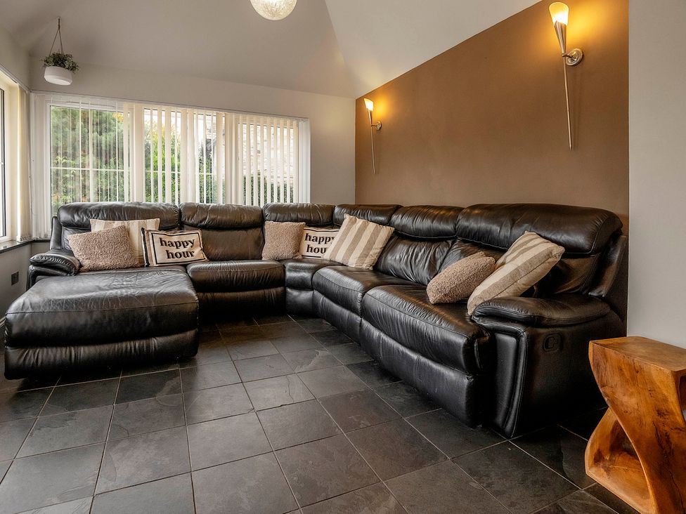 A living room with a leather sofa and cushions at Taighean Anndra in Killin