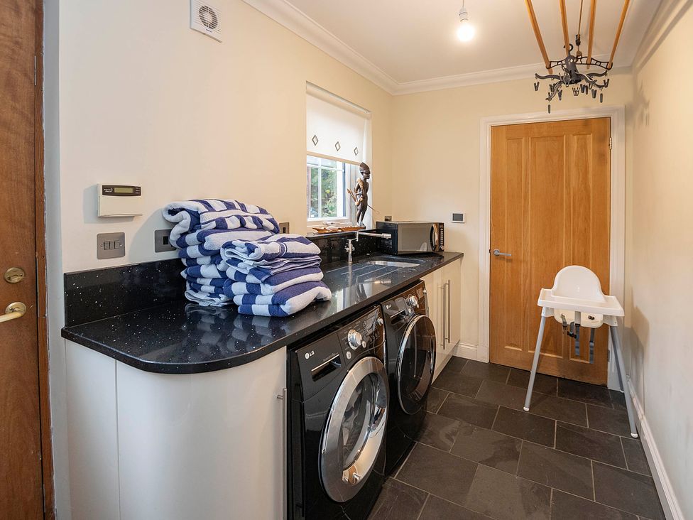 A laundry room with a washer, dryer, and towels at Taighean Anndra in Killin