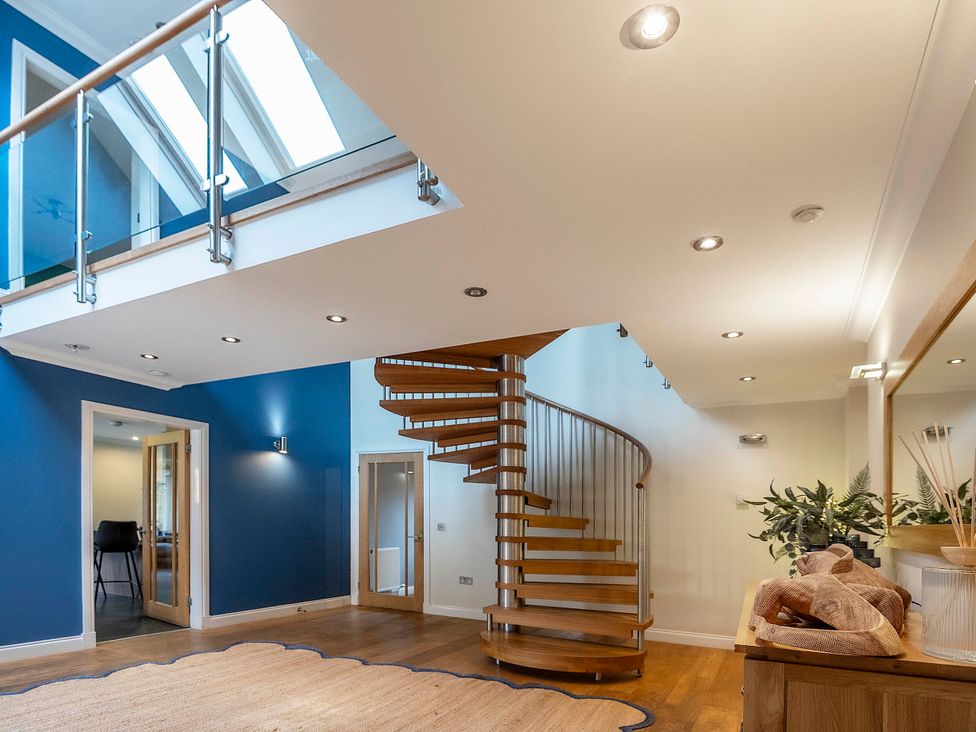 A hallway featuring a spiral staircase and light fixtures at Taighean Anndra in Killin