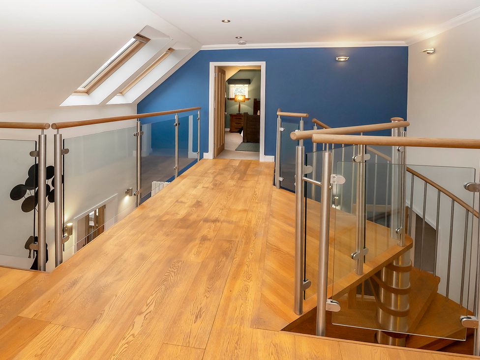 A hallway with wooden flooring and glass railings at Taighean Anndra in Killin