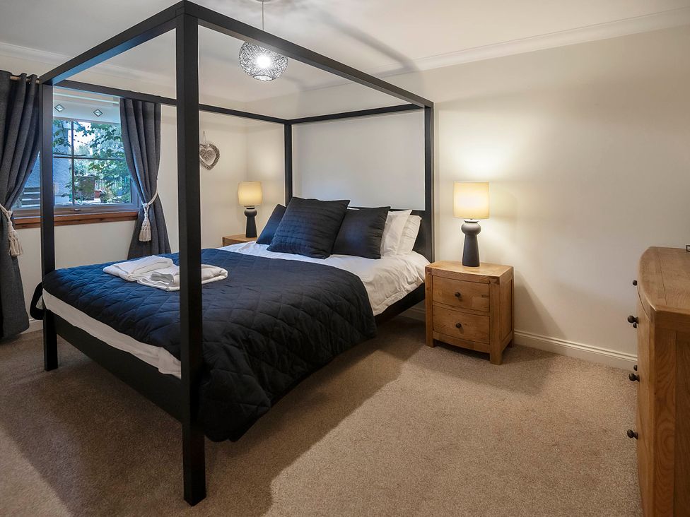 A bedroom with a four-poster bed and nightstand at Taighean Anndra in Killin