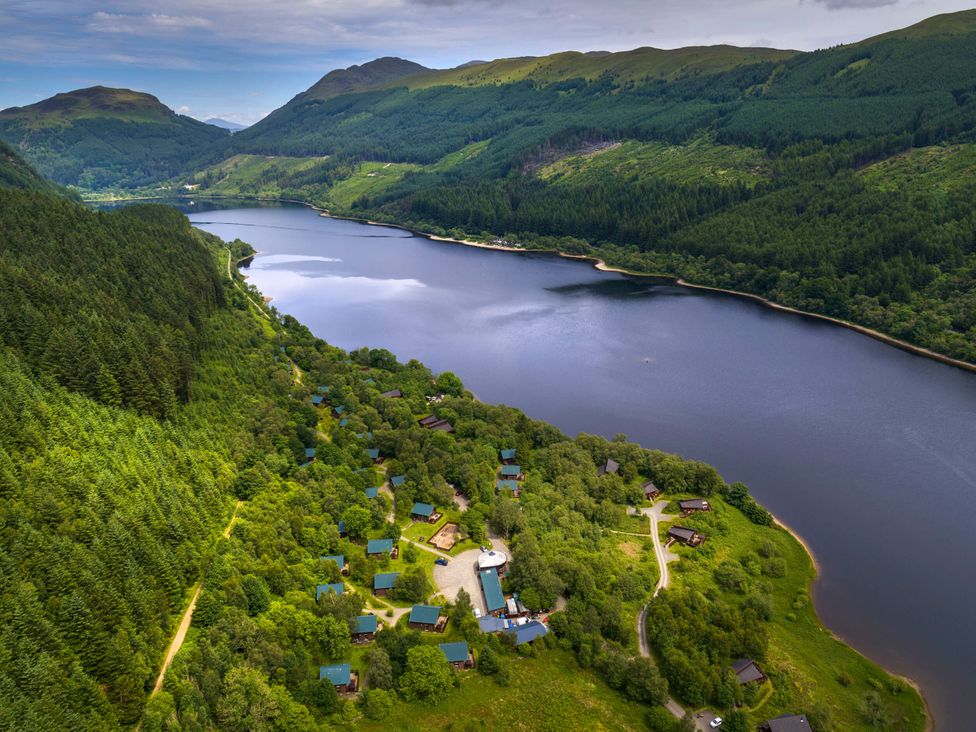 An aerial view of a lake with cabins and forest at Strathyre Golden Oak Lochside, Strathyre, Ben Ledi