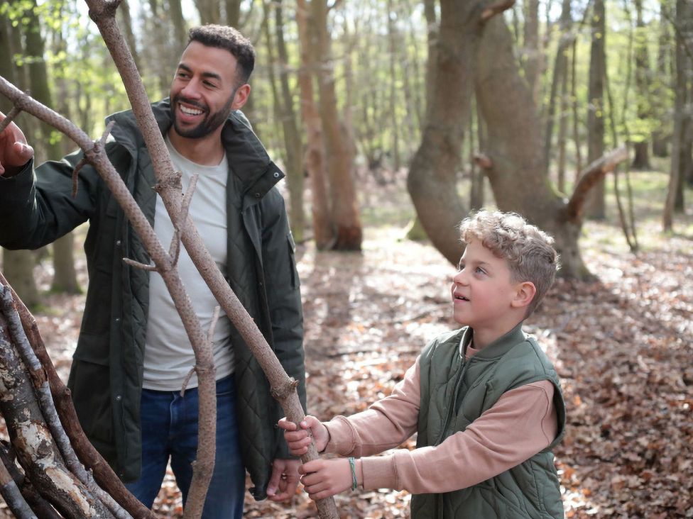 A man and a boy interacting with sticks in a forest at Strathyre Golden Oak Lochside Strathyre, Ben Ledi
