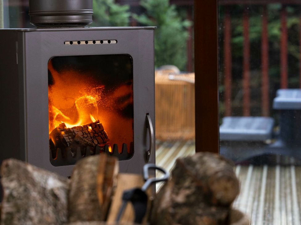 A wood stove with fire and logs at Blackwood Forest Golden Oak in Blackwood Forest