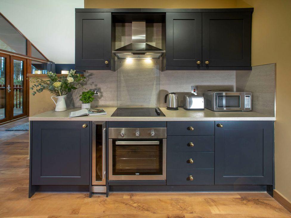 A kitchen with cabinets, an oven, microwave, kettle, and sink at Delamere Forest Golden Oak Hideaway Delamere Forest