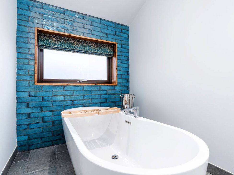 A bathroom with a bathtub and window at Delamere Forest Golden Oak Hideaway Delamere Forest