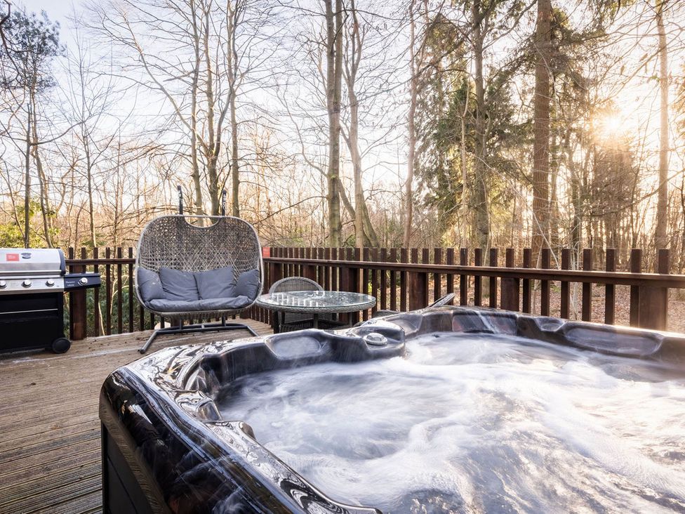 An outdoor area with a hot tub and seating at Delamere Forest Golden Oak Hideaway in Delamere Forest