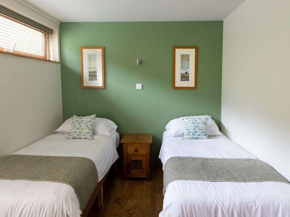 A bedroom with two beds and a wooden table at Deerpark Classic Golden Oak Waterside in Deerpark Forest