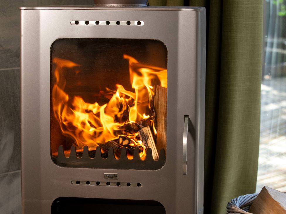 A wood stove with flames and firewood at Cropton Golden Oak Cropton Forest