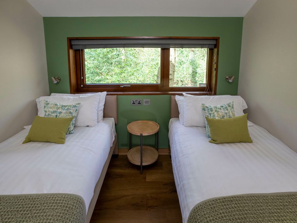 Two single beds with green cushions and a side table at Delamere Forest Golden Oak in Delamere Forest