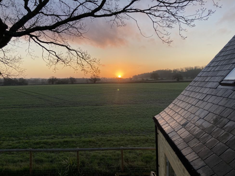 A sunset view over a field with a tree and roof at 4 Wellacres Cottage Draycott near Moreton-In-Marsh