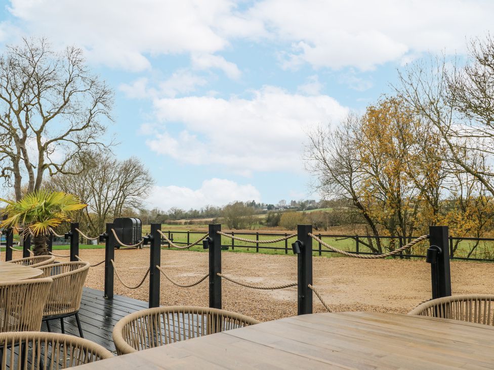 An outdoor area with a table and chairs overlooking a landscape at Squirrel's Nest South Luffenham near Edith Weston
