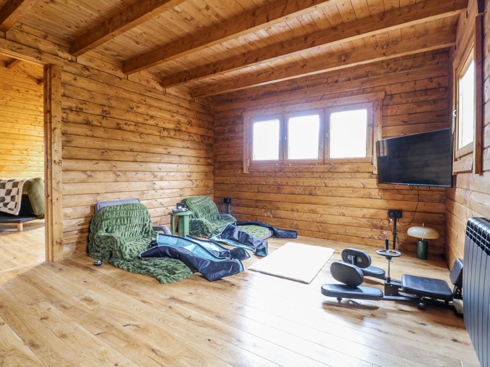 A living room with wooden walls and exercise equipment at Squirrel's Nest South Luffenham near Edith Weston
