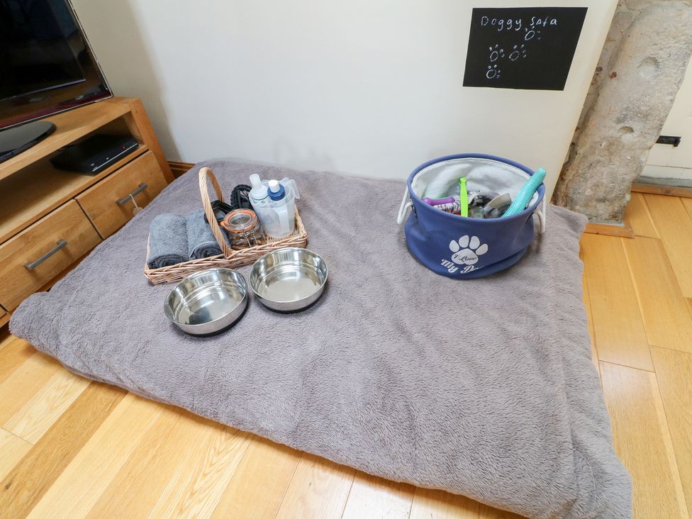 A dog bed with bowls and a basket of grooming supplies at 33 Main Road Higham Derbyshire