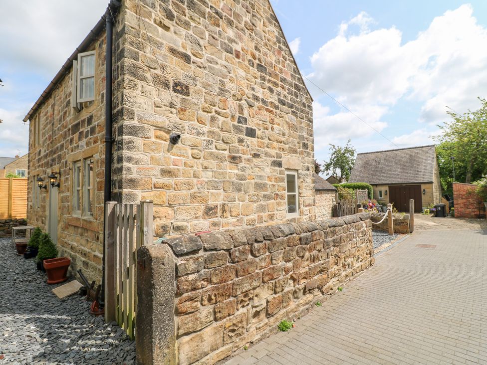 A side view of a stone house with a wall and potted plants at 33 Main Road Higham Derbyshire