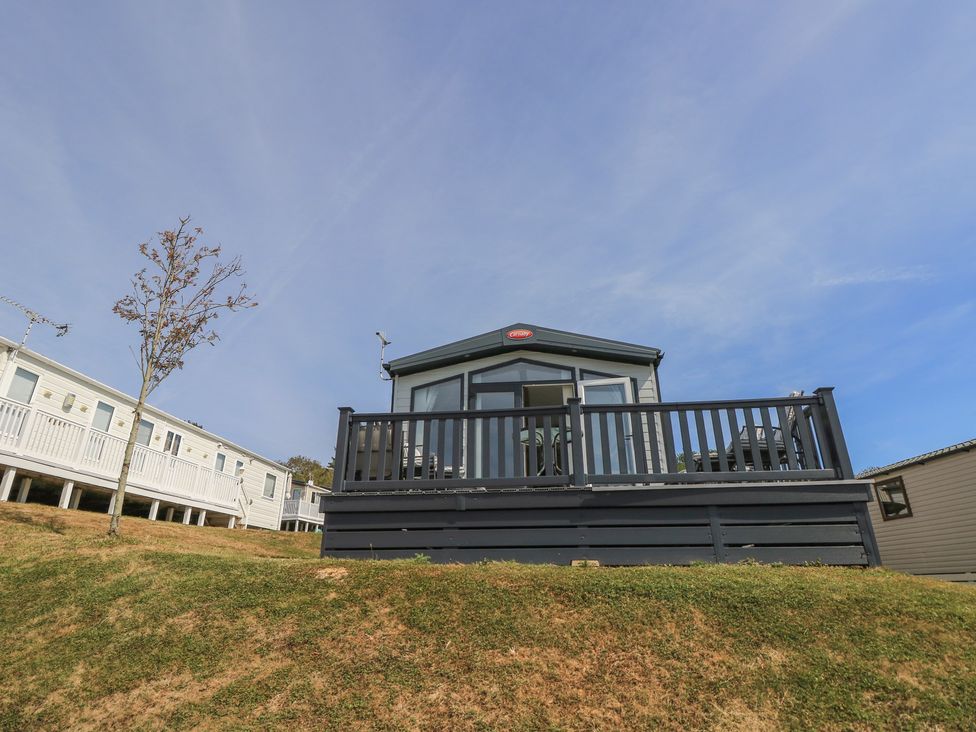 A caravan with a deck and tree at 31 Crosswinds in Bembridge