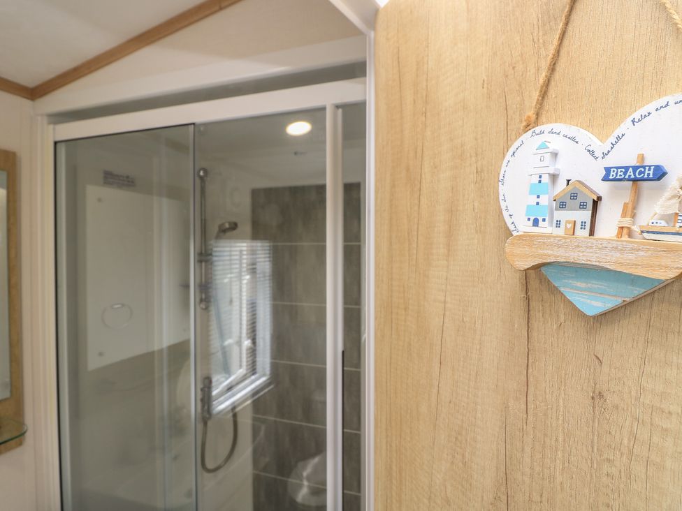 A shower area with a decorative sign in a bathroom at 31 Crosswinds in Bembridge