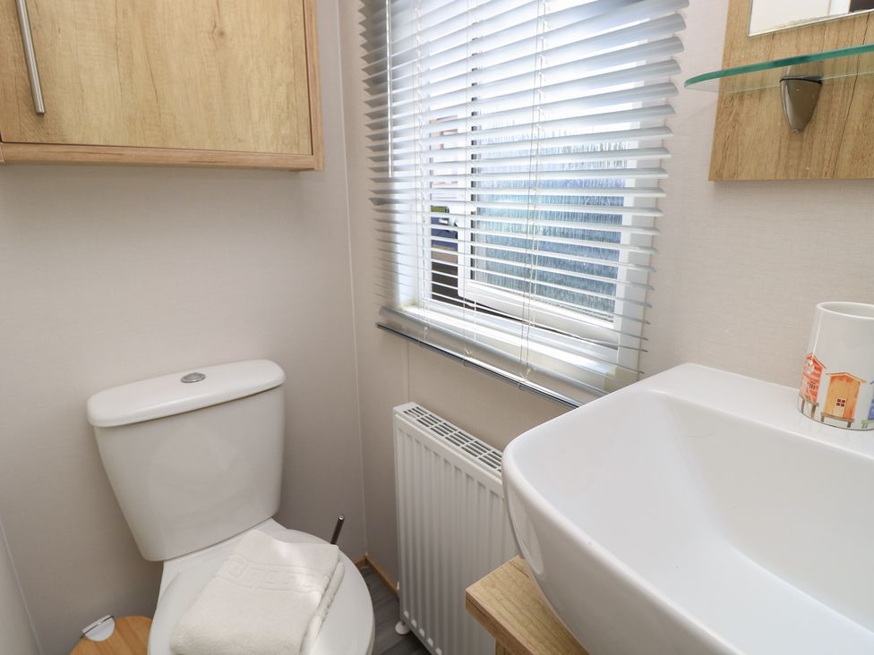 A bathroom with a toilet, sink, and window at 31 Crosswinds, Bembridge