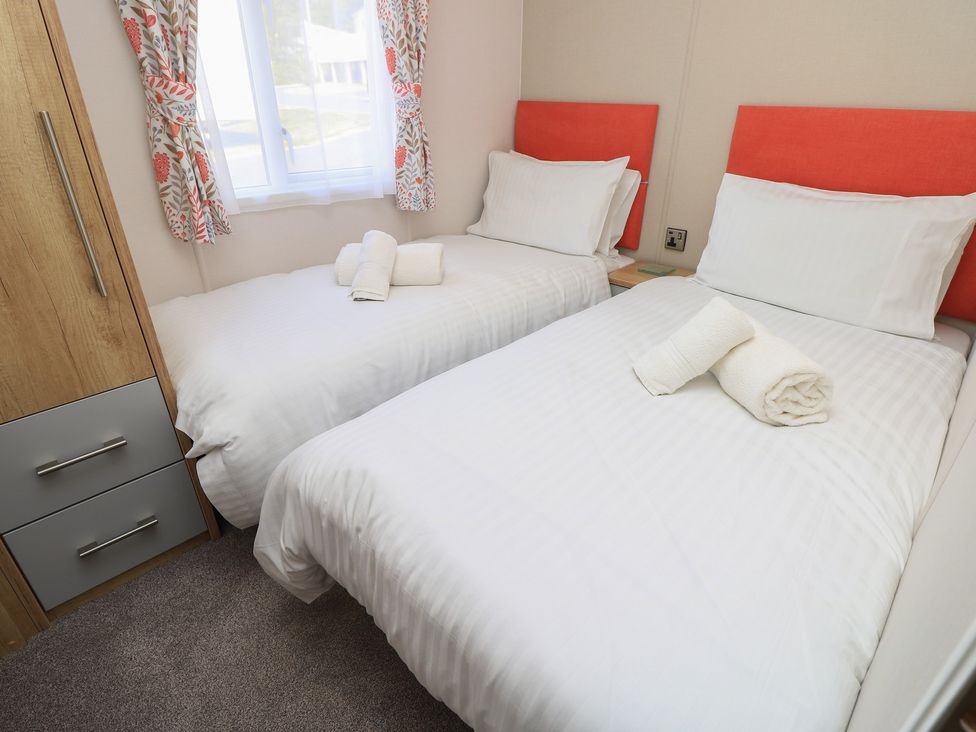 A bedroom with two beds and a wardrobe at 31 Crosswinds in Bembridge