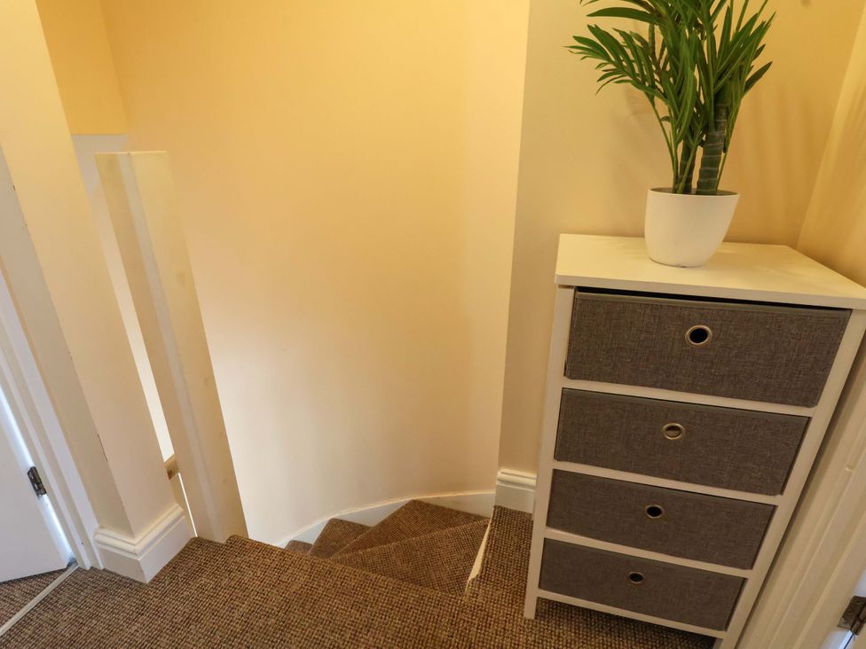 A staircase with a drawer unit and plant at Hill View in Bala