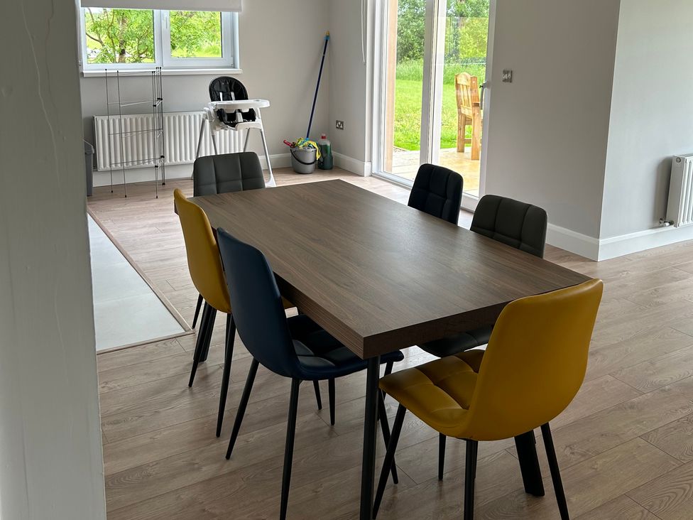 A dining room with a wooden table and colorful chairs at 30 River Run in Belturbet