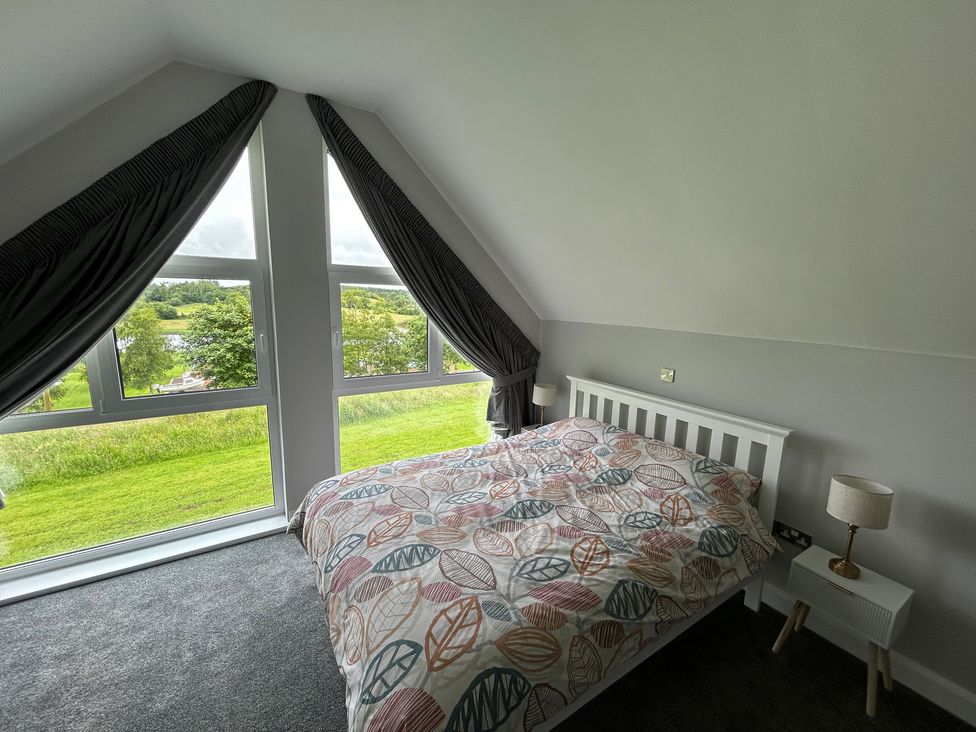 A bedroom with a bed and windows at 30 River Run in Belturbet