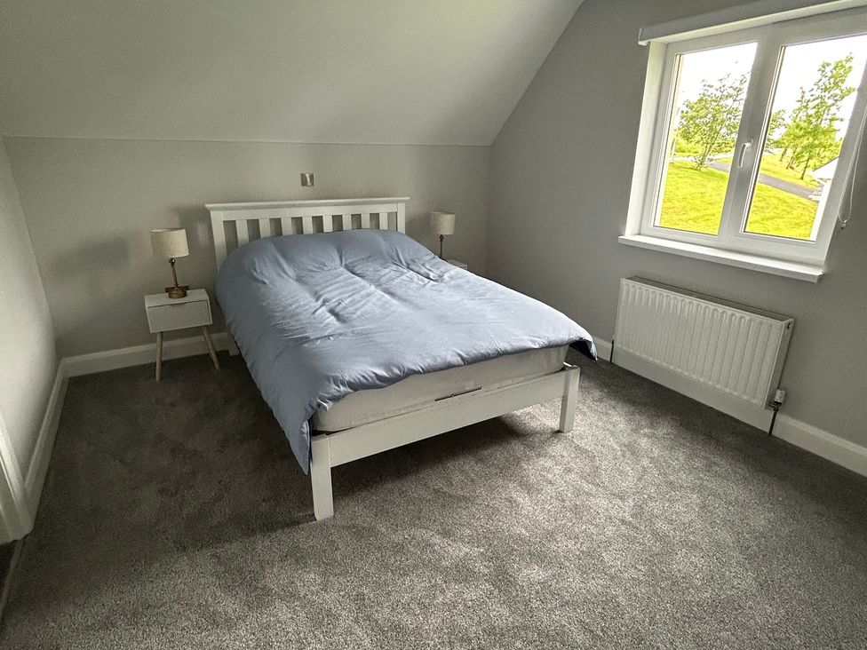 A bedroom with a bed and nightstand at 30 River Run in Belturbet