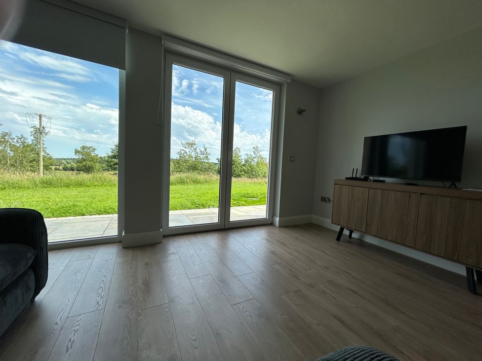 A living room with a television and large windows at 30 River Run, Belturbet, County Cavan