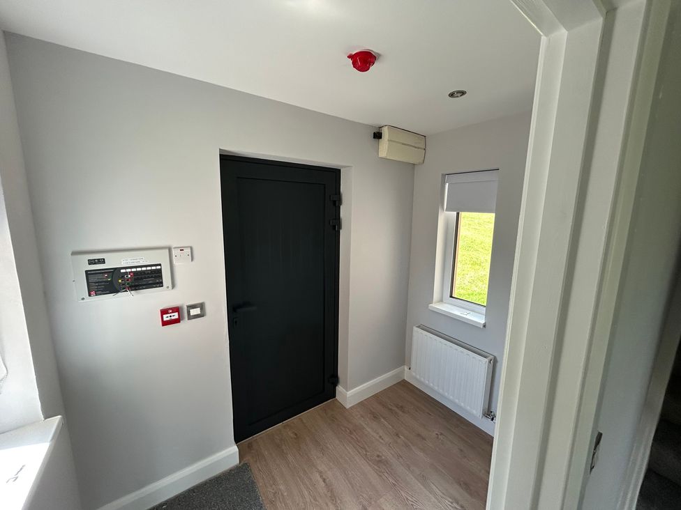 A hallway with a door and control panel at 30 River Run, Belturbet, County Cavan