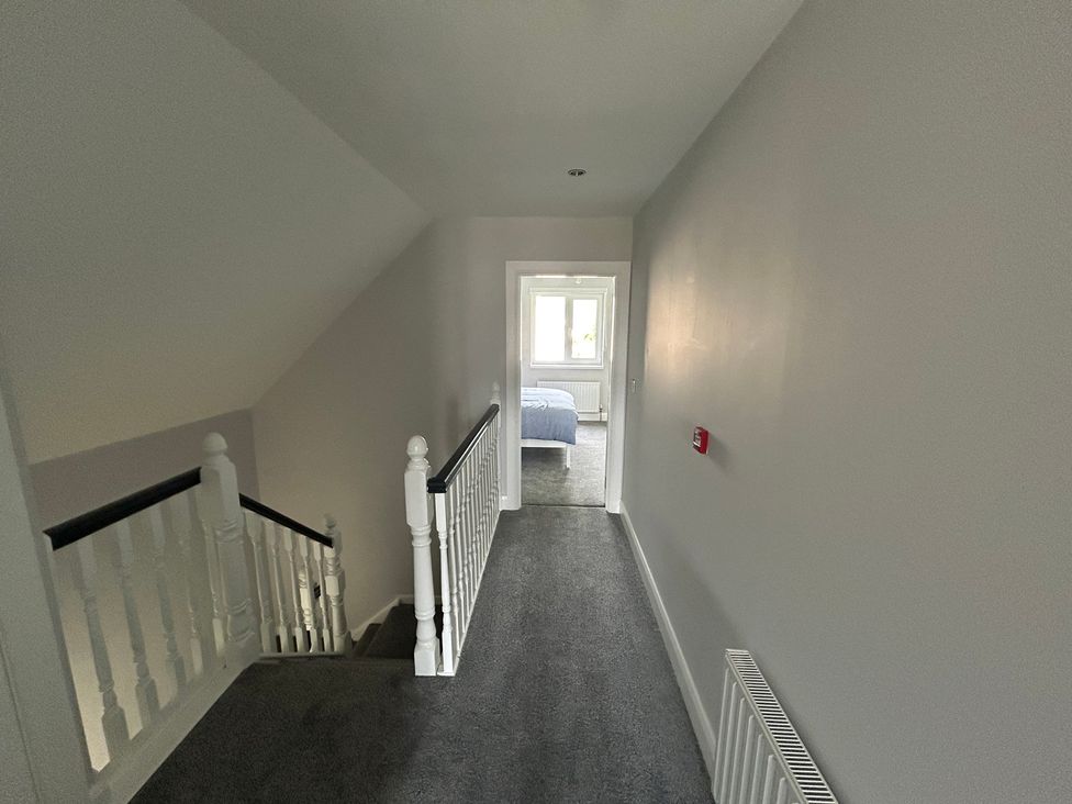 A hallway with a staircase and door at 30 River Run in Belturbet, County Cavan