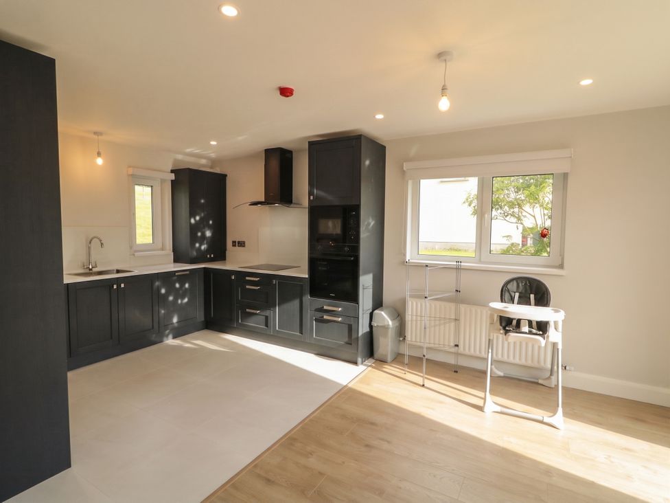 A kitchen with cabinets, sink, and a high chair at 30 River Run, Belturbet, County Cavan