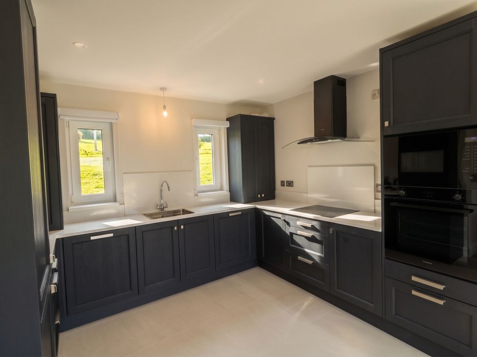 A kitchen with cabinets, sink and windows at 30 River Run in Belturbet, County Cavan