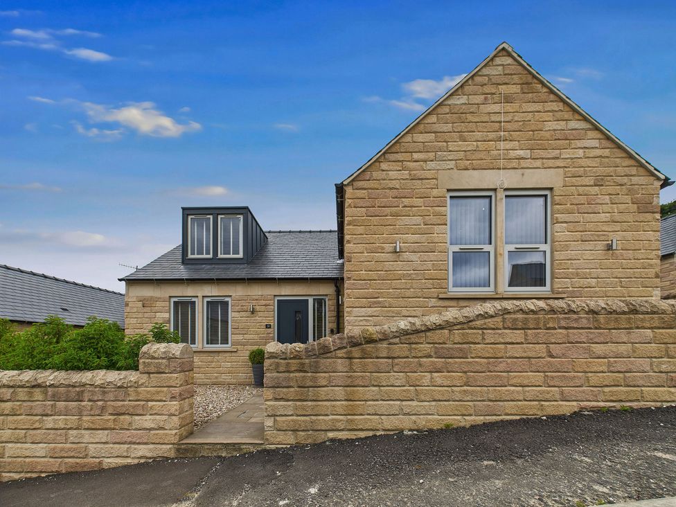A house with a stone wall and garden at Oakwood Lodge in Tansley