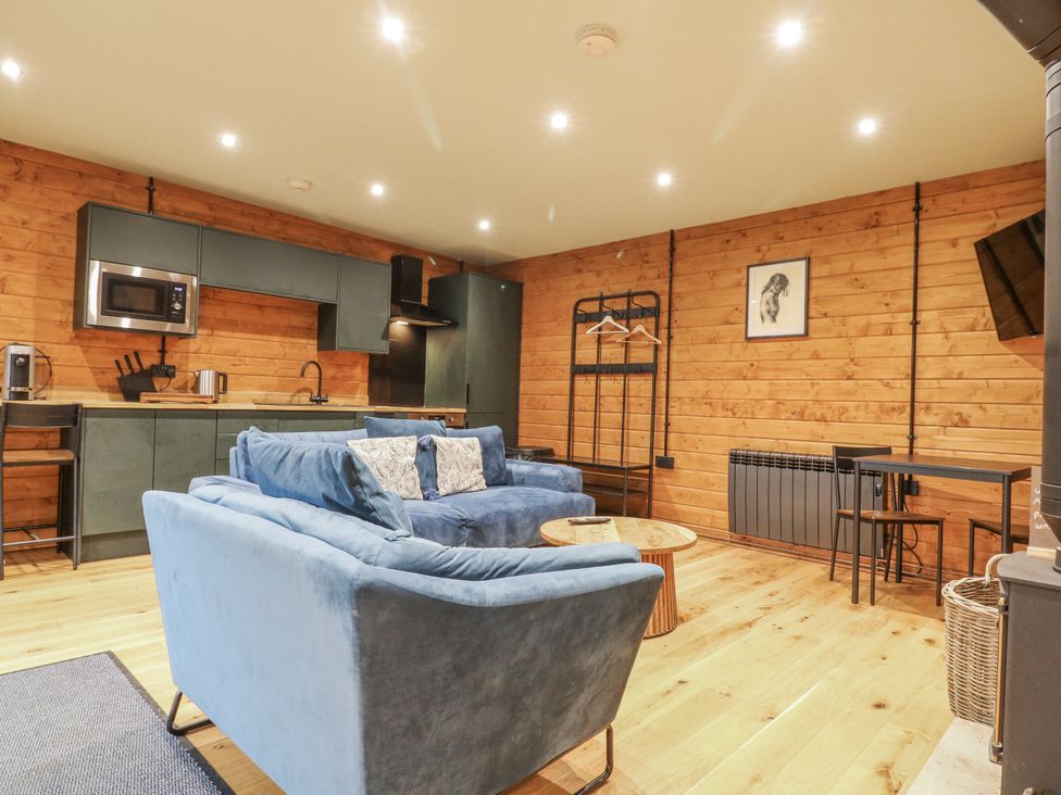 A living room with a sofa and kitchen area at Otter's View in South Luffenham near Edith Weston