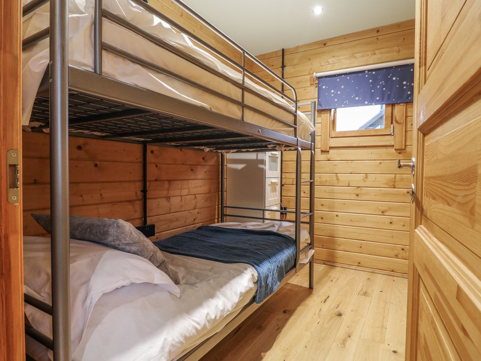 A bedroom with a bunk bed and wooden walls at Otter's View South Luffenham near Edith Weston