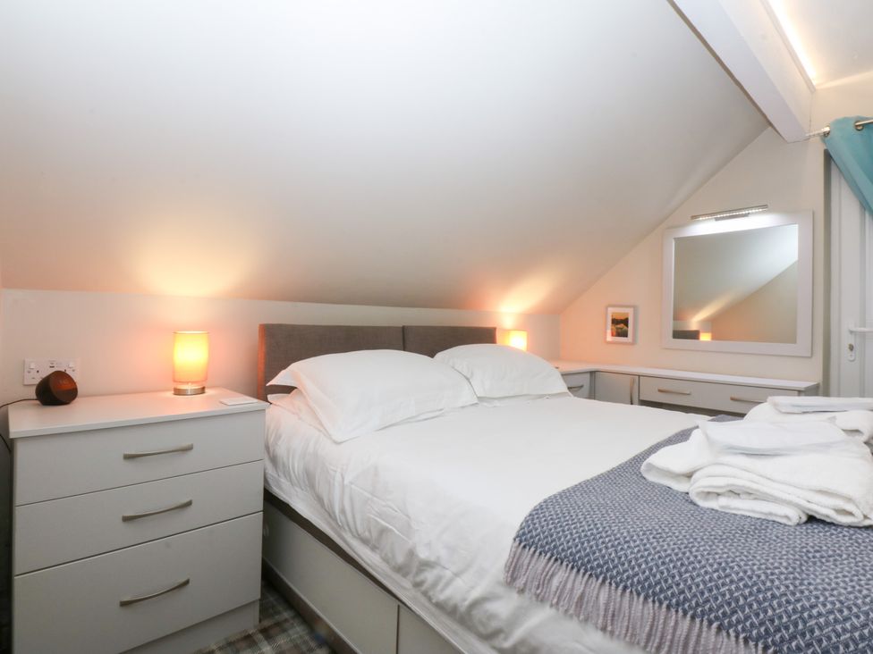 A bedroom with a bed and nightstand at Pine Cottage Dinas Dinlle