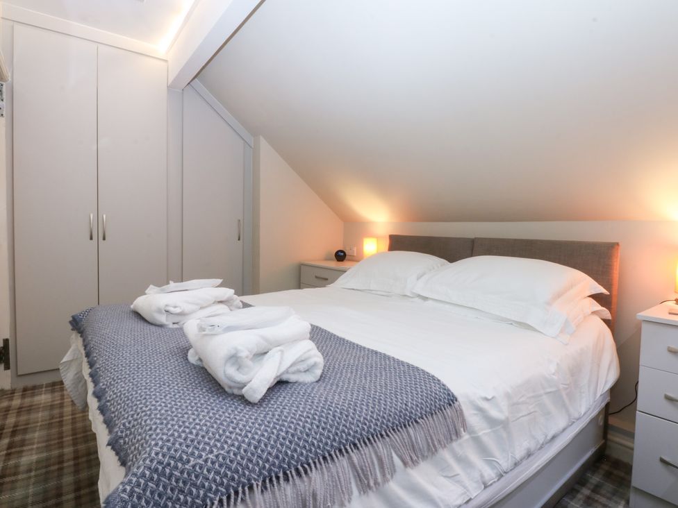 A bedroom with a bed and wardrobe at Pine Cottage in Dinas Dinlle