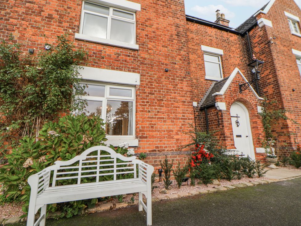 An exterior view of a house with a garden and a bench at The House at School Farm in Hassall near Haslington